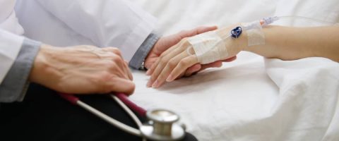 יד של רופא אוחזת יד של אישה עם אינפוזיה