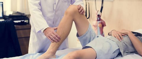 רופא בודק את רגלו של אדם על גבי מיטת טיפולים