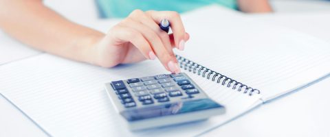 יד של אישה מחשבת במחשבון כיס על שולחן