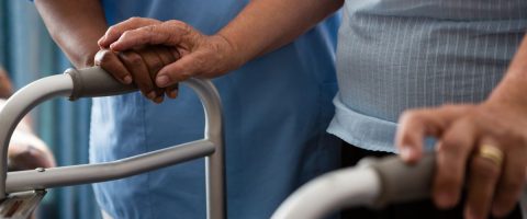 אישה מתהלכת עם הליכון בליווי מסייעת