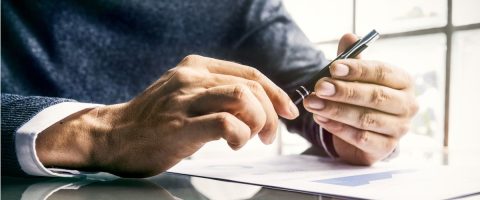 יד אוחזת בעט מעל גיליון נייר