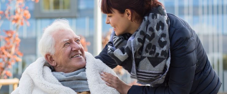 אישה צעירה רוכנת לעברו של אדם מבוגר מחייך