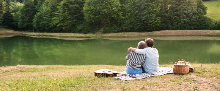 בני זוג יושבים מחובקים על שפת אגם