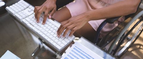 אישה יושבת על כיסא גלגלים ומקלידה על מחשב