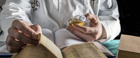 רופא מחזיק תרופה וקורא בספר