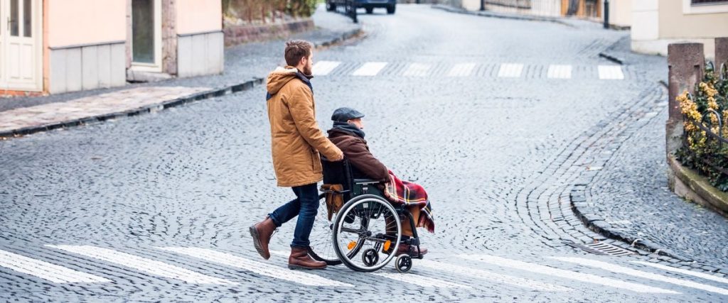 בחור צעיר מנייד אדם מבוגר על כיסא גלגלים